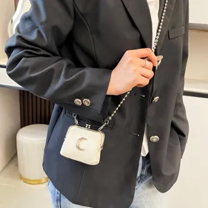 Mini kiss-lock crossbody bag with metal moon decor and chic chain strap for women.