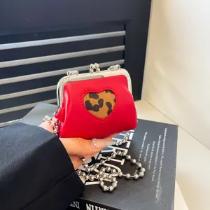 Mini red kiss lock crossbody bag with leopard heart pattern and silver chain strap.