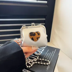 Mini silver kiss-lock crossbody bag with leopard heart cutout and chunky chain strap.