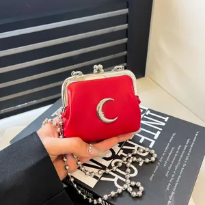 Red mini kiss-lock crossbody bag with silver moon charm and chunky chain strap stylish.