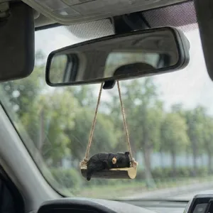 Détail en gros plan d'un mignon pendentif de voiture ours noir dormant sur une balançoire.