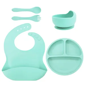 Silicone baby feeding set with suction plate, bowl, bib, spoon, and fork in mint green.