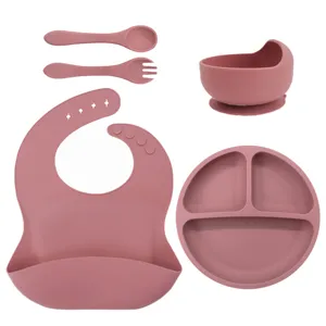 Silicone baby feeding set with divided plate, suction bowl, bib, spoon, and fork for toddlers.