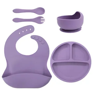 Silicone baby feeding set with divided suction plate, bowl, bib, spoon and fork in purple.