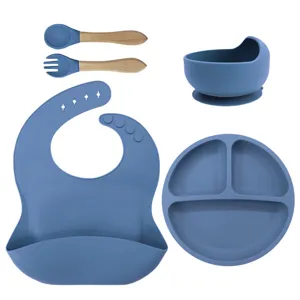 Silicone baby feeding set with divided plate bowl bib and wooden spoon fork for toddlers.
