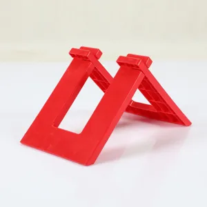 Detailed view of the red plastic balance bike parking stand, showing sturdy triangle structure.