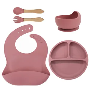 Silicone baby feeding set detail showing divided plate, suction bowl, and wooden spoon.
