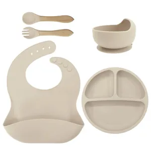 Baby silicone feeding set detail view, featuring divided suction plate, bowl, bib, spoon and fork.