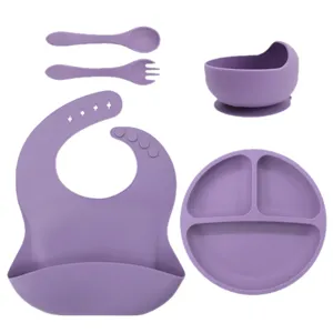 Baby silicone feeding set with divided suction plate, bowl, bib, spoon, and fork for toddlers.