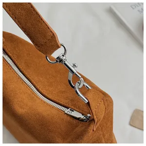 Brown suede shoulder pillow bag detail, featuring silver metal hardware and zipper craftsmanship.