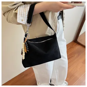 Black suede underarm shoulder bag detail view showcasing soft texture and stylish beaded charm.