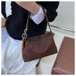 Brown suede underarm shoulder bag with front zipper pocket and cute wooden bead charm detail.