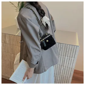 Vista detallada de un elegante bolso de hombro acolchado de terciopelo negro con cierre floral.