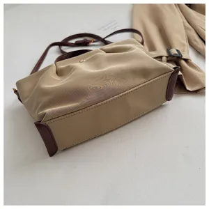Detailed view of the stylish khaki nylon shoulder bag with brown leather trim and strap.