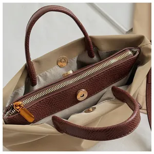 Detailed view of women's nylon handbag with brown textured handles and inner pocket.