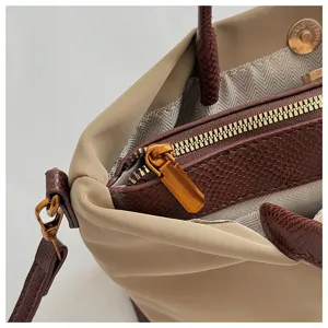 Close-up of stylish nylon tote handbag detail with golden zipper and fine leather trim.