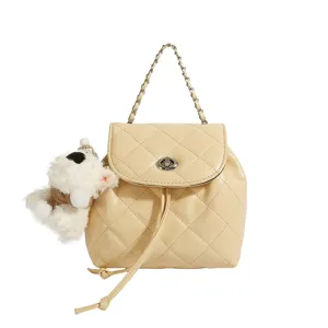 Close-up detail of the quilted beige backpack with chain handle, twist lock and cute plush puppy charm.