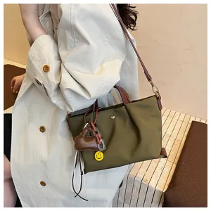 Detailed view of olive green nylon crossbody bag with brown leather straps and cute charms.