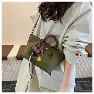 Close-up of stylish nylon crossbody handbag with brown handles and charms for daily use.