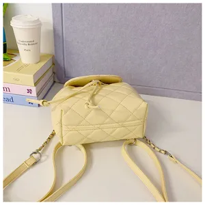 Yellow quilted leather mini backpack with chain straps, stylish travel shoulder bag detail view.
