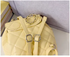 Detailed view of a yellow quilted leather mini backpack with chain strap and buckles.