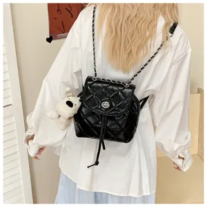 Detail view of black quilted leather mini backpack with metal chain strap and cute bear charm.