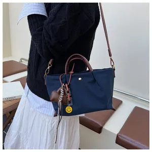 Detail view of the stylish dark blue nylon women shoulder bag with brown handles and cute charm.