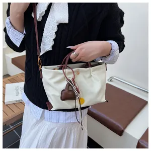 Detailed shot of casual nylon crossbody bag with chic contrast handles and cute pendant.