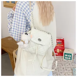 Detailed view of white quilted patent leather backpack with chain strap and cute plush pendant.