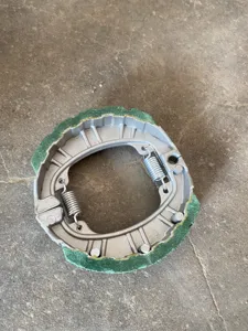 Nahaufnahme einer Motorrad-Trommelbremsbacke mit integrierter Feder und Reibbelag-Detail.