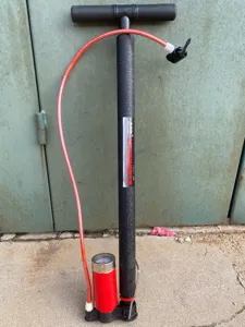 Detailansicht einer tragbaren Mehrzweck-Stahl-Standpumpe mit Manometer und rotem Schlauch.