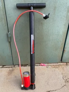Detailansicht einer schwarzen Stahl-Standpumpe mit Manometer und rotem Reifenschlauch.