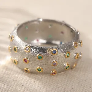 Vista dettagliata dell'anello largo strutturato con pietre di zirconia sintetica multicolore.