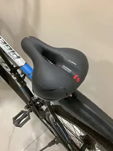 Ergonomic thick black bicycle saddle with ventilation hole mounted on mountain bike detail view
