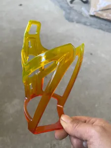 Detailed view of a bright yellow orange transparent plastic bicycle water bottle cage frame.
