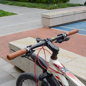 Closeup of mountain bike handlebar grips, brown rubber anti-slip design for secure cycling.