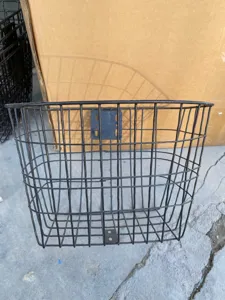Dettaglio del cestino anteriore per bicicletta in ferro nero con design a rete metallica.
