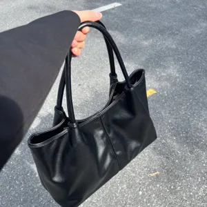 Black solid color minimalist tote shoulder bag, casual large capacity handbag detail view.