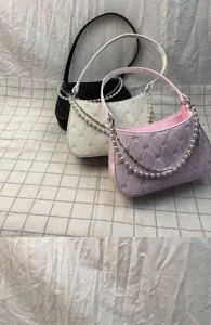 Detail shot of trendy women shoulder bags with pearl chains and bow quilted pattern designs.