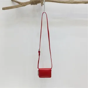Detail display of the red mini crossbody bag featuring fine leather strap and clean form.