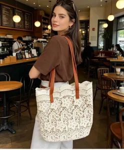 Gros plan élégant d'un sac cabas en dentelle blanche avec anses marron en café.