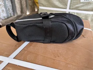 Dettaglio borsa da sella per bicicletta nera, materiale resistente con cinghia a sgancio rapido.