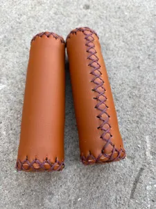 Detailed view of vintage brown PU leather bicycle handlebar grips with hand stitching.