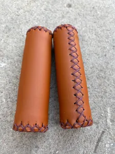 Detailed view of vintage bicycle handlebar grips, brown PU leather with hand stitching.