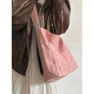 Detail view of the stylish pink slouchy shoulder bag worn with a brown leather jacket.