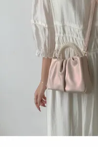 Detail shot of the pleated cloud mini handbag featuring an elegant pearl handle and strap.