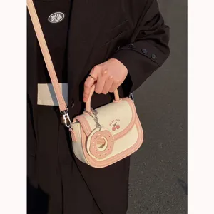 Chic borsa a sella mini beige e rosa con ciondolo a ciambella e ricamo di ciliegie.