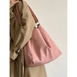 Detail shot of a large pink slouchy shoulder tote bag worn with a stylish beige trench coat.