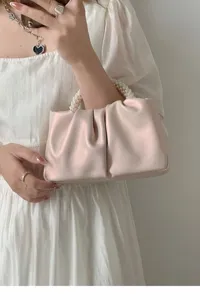 Detailed view of fashionable ruched cloud handbag with elegant pearl handle design.