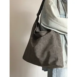Detail shot of a slouchy dark grey shoulder tote bag worn with a denim jacket for daily use.